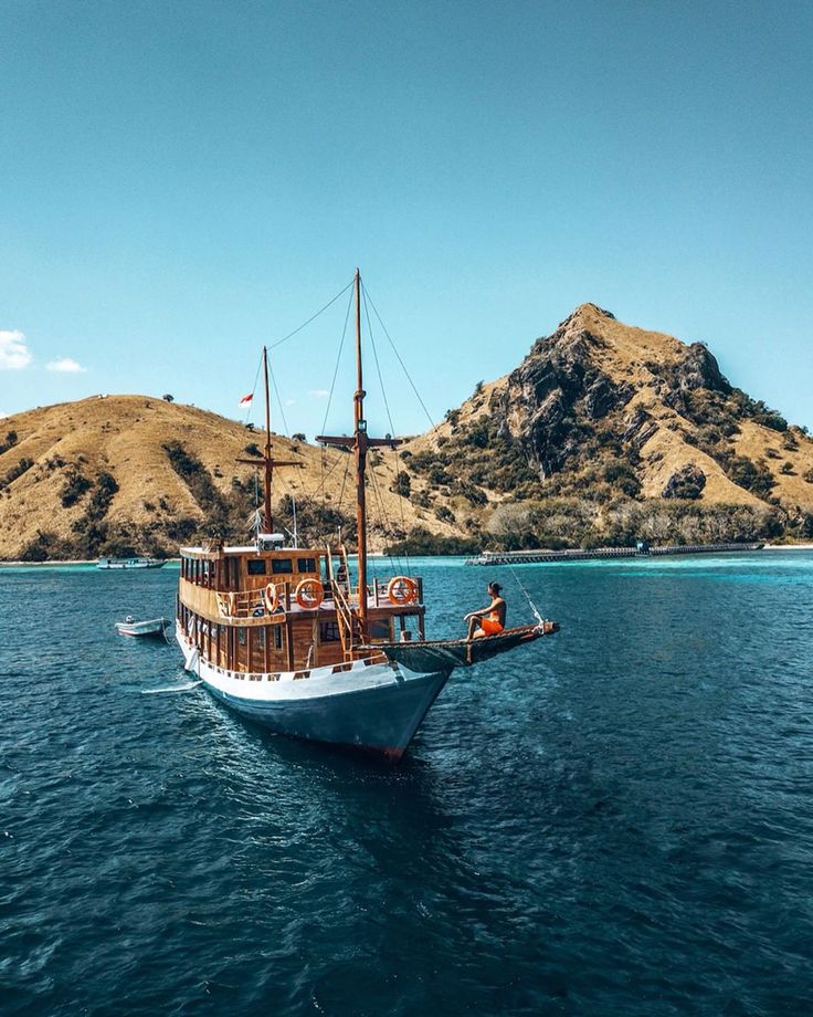 Traditional phinisi sailing boat cruising through Labuan Bajo waters at sunset